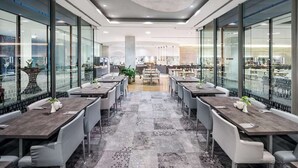 Un comedor moderno con paredes de vidrio, varias mesas y sillas.