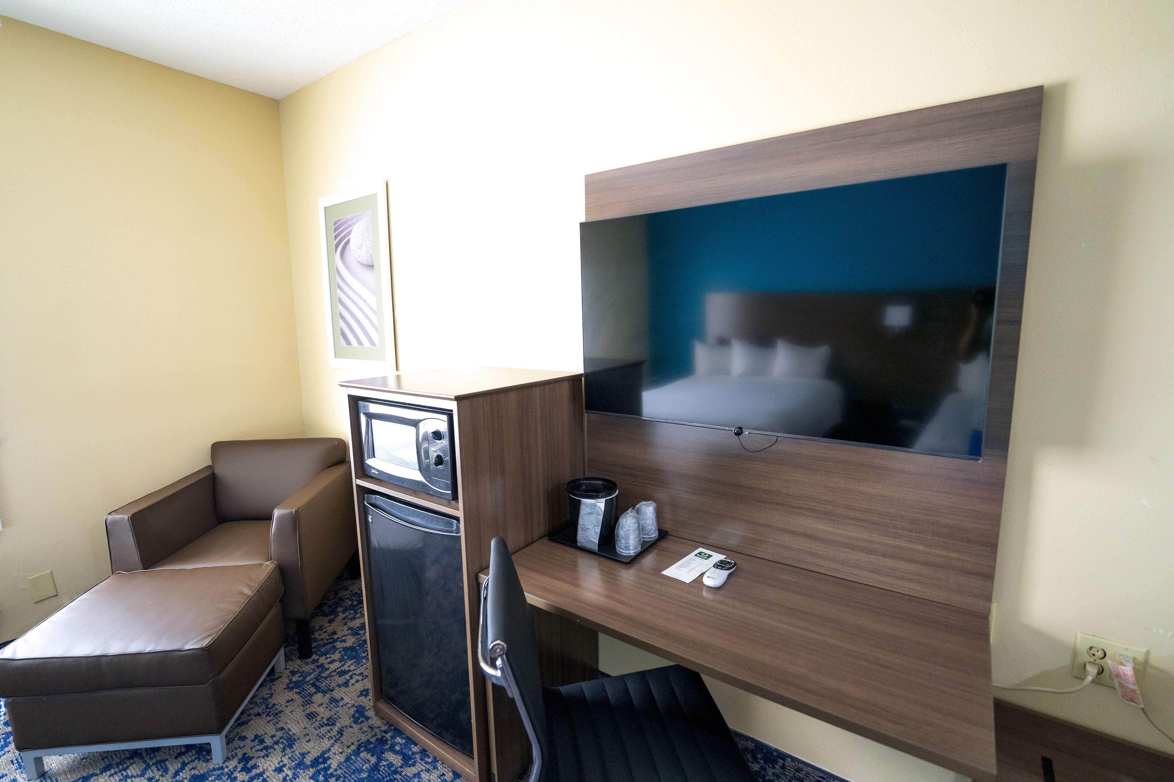 Una habitación de hotel con una cama, un escritorio, una silla, un televisor y un microondas.