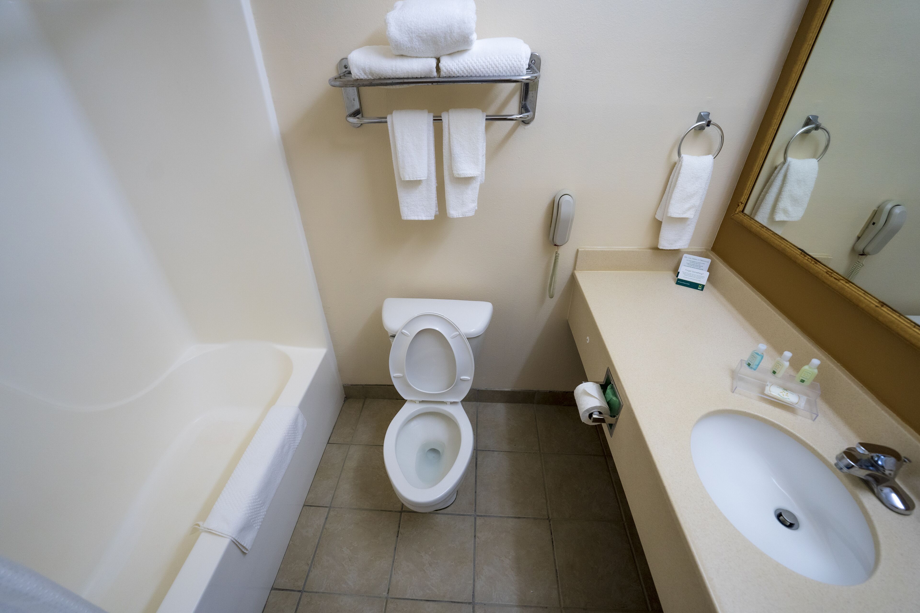 A bathroom with a toilet, sink, and a towel rack with towels.
