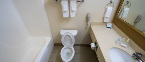 A bathroom with a toilet, sink, and a towel rack with towels.