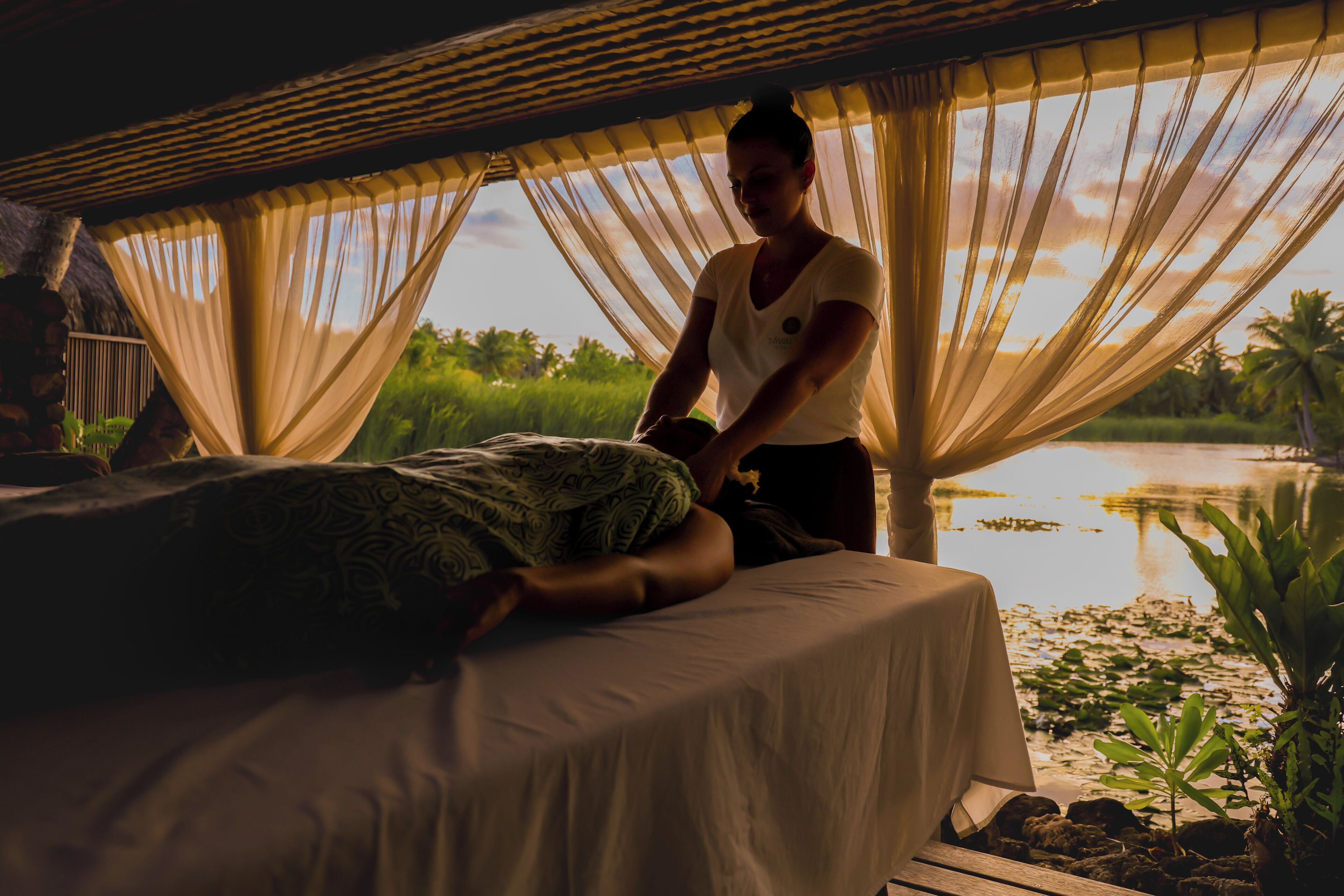 A person lying on a bed in a room with a view of a lake and palm trees.