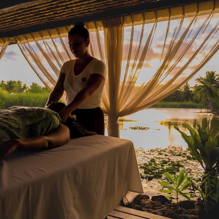 A person lying on a bed in a room with a view of a lake and palm trees.