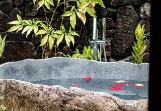 A stone wall with a water feature, including a fountain and a rock basin.