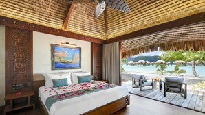 A bedroom with a bed, a painting, and a view of a beach. - Le Taha'a by Pearl Resorts (Taha'a)