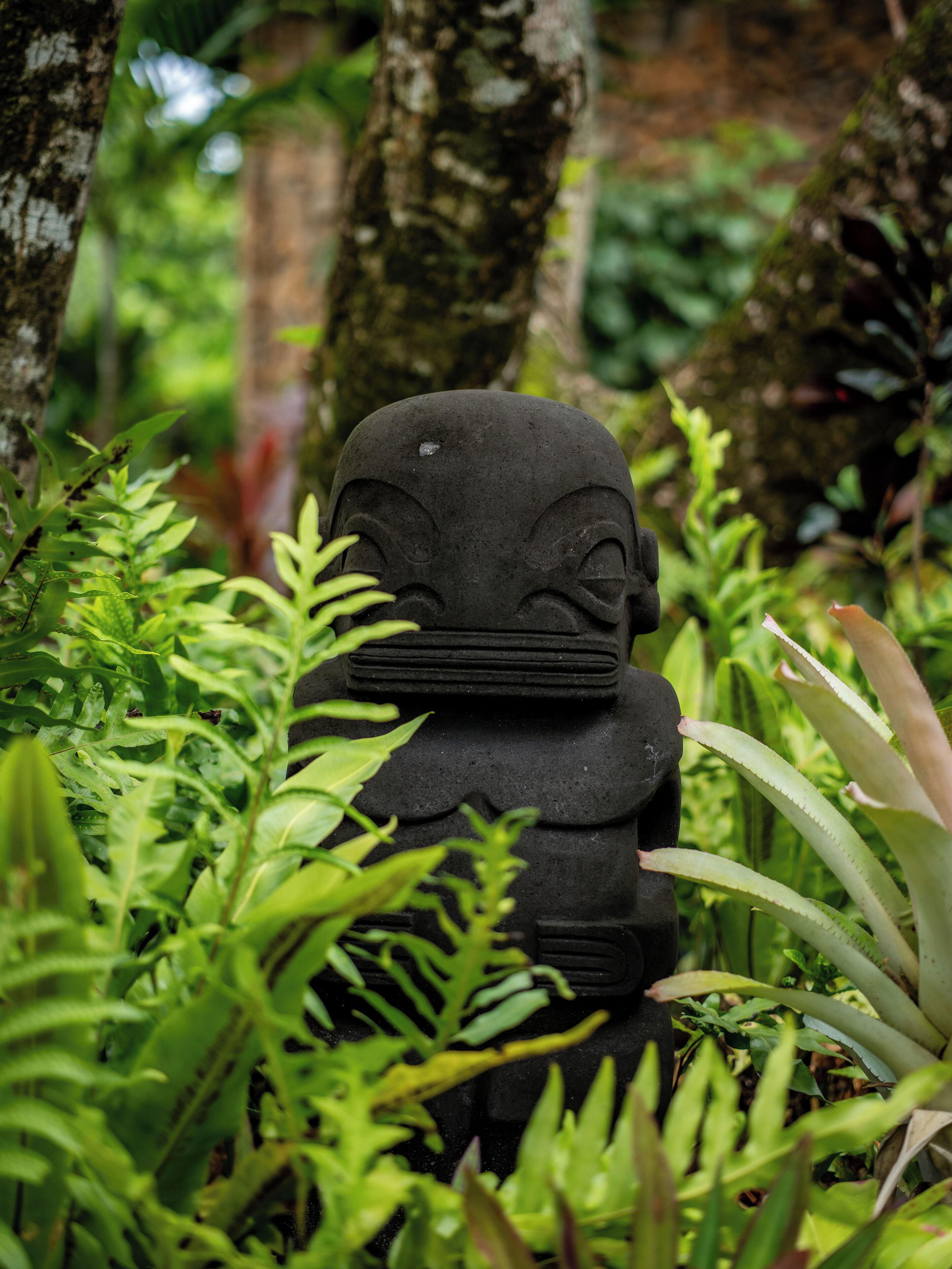 A stone statue surrounded by lush green foliage.