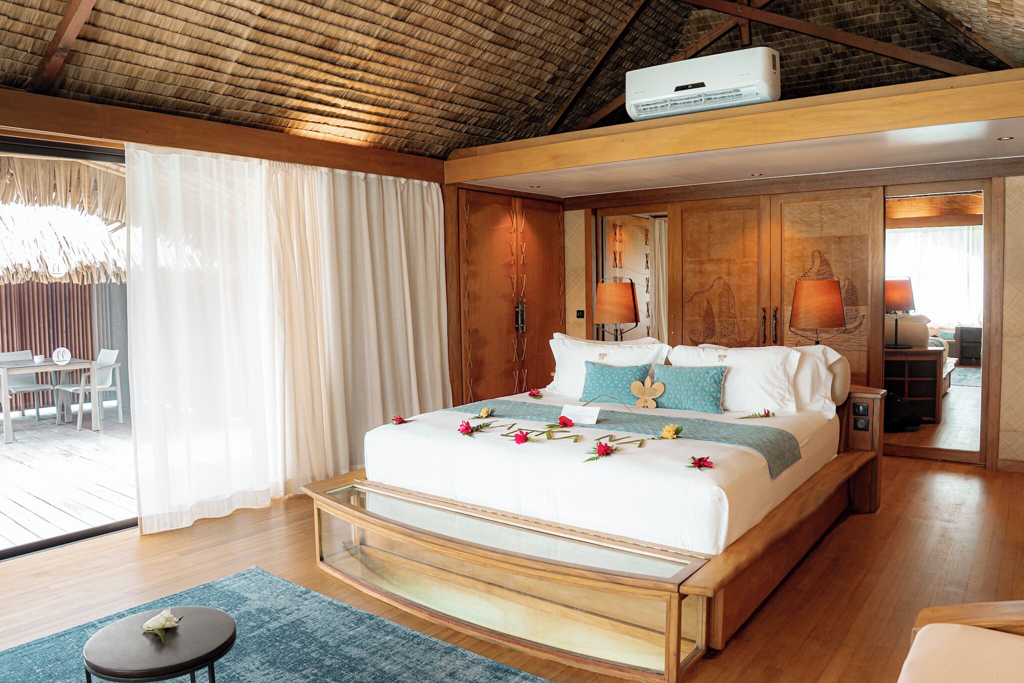 Un dormitorio amplio con una cama grande, cabecera de madera y vistas al exterior.