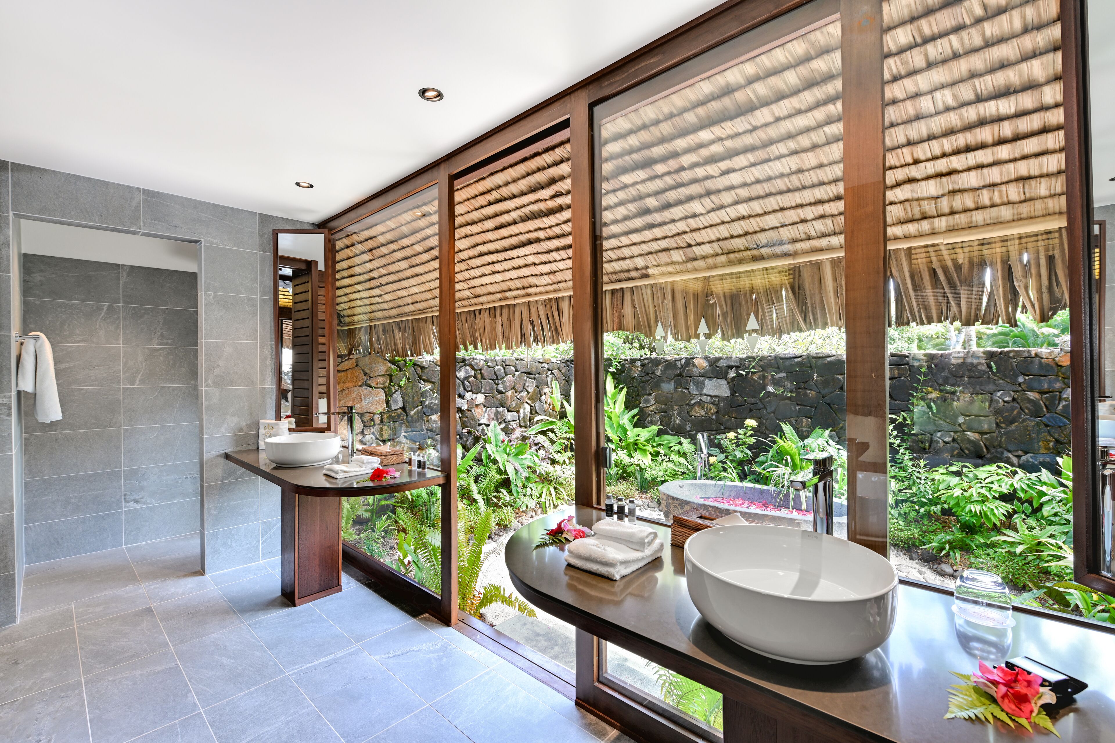 Un baño moderno con un ventanal grande, una pared de piedra y un techo de madera.