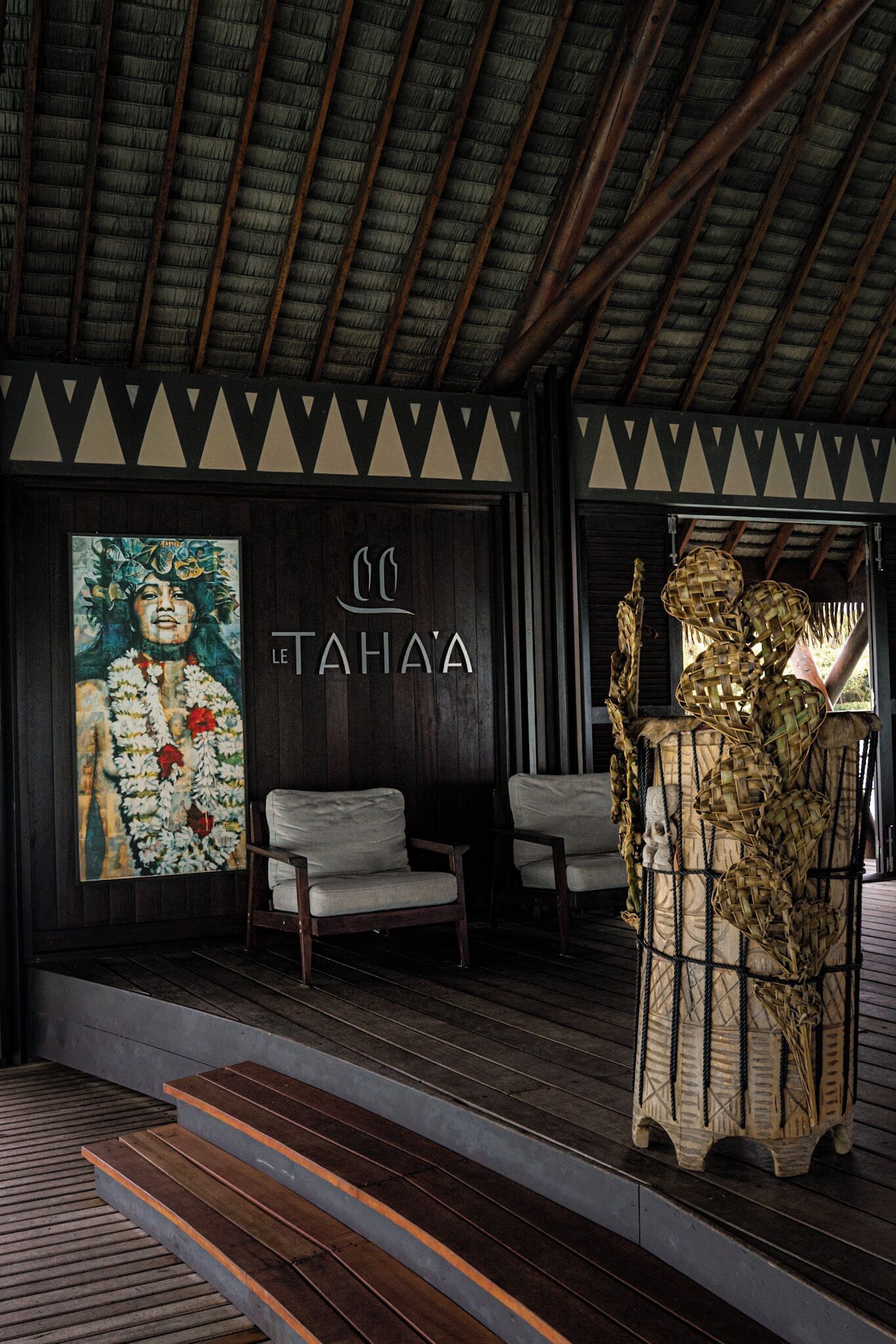 A wooden staircase leading to a seating area with a mural and a decorative basket.