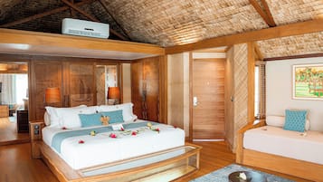 A spacious bedroom with a large bed, a wooden bench, a sofa, and a ceiling fan.