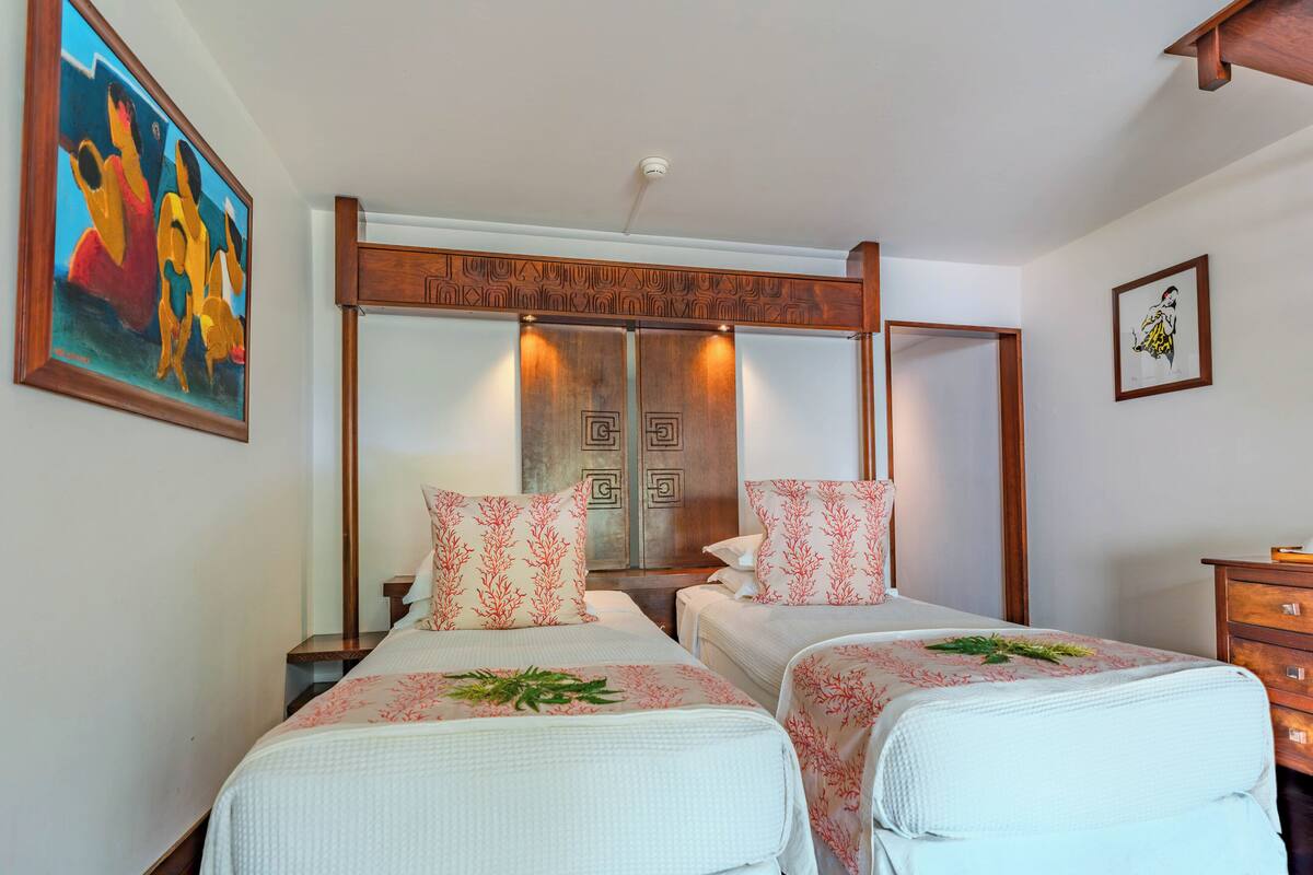 A hotel room with two beds, a wooden headboard, a large mirror, and artwork on the walls.