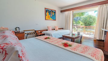 A hotel room with two beds, a painting on the wall, a balcony with a view, and a table with a flower arrangement.
