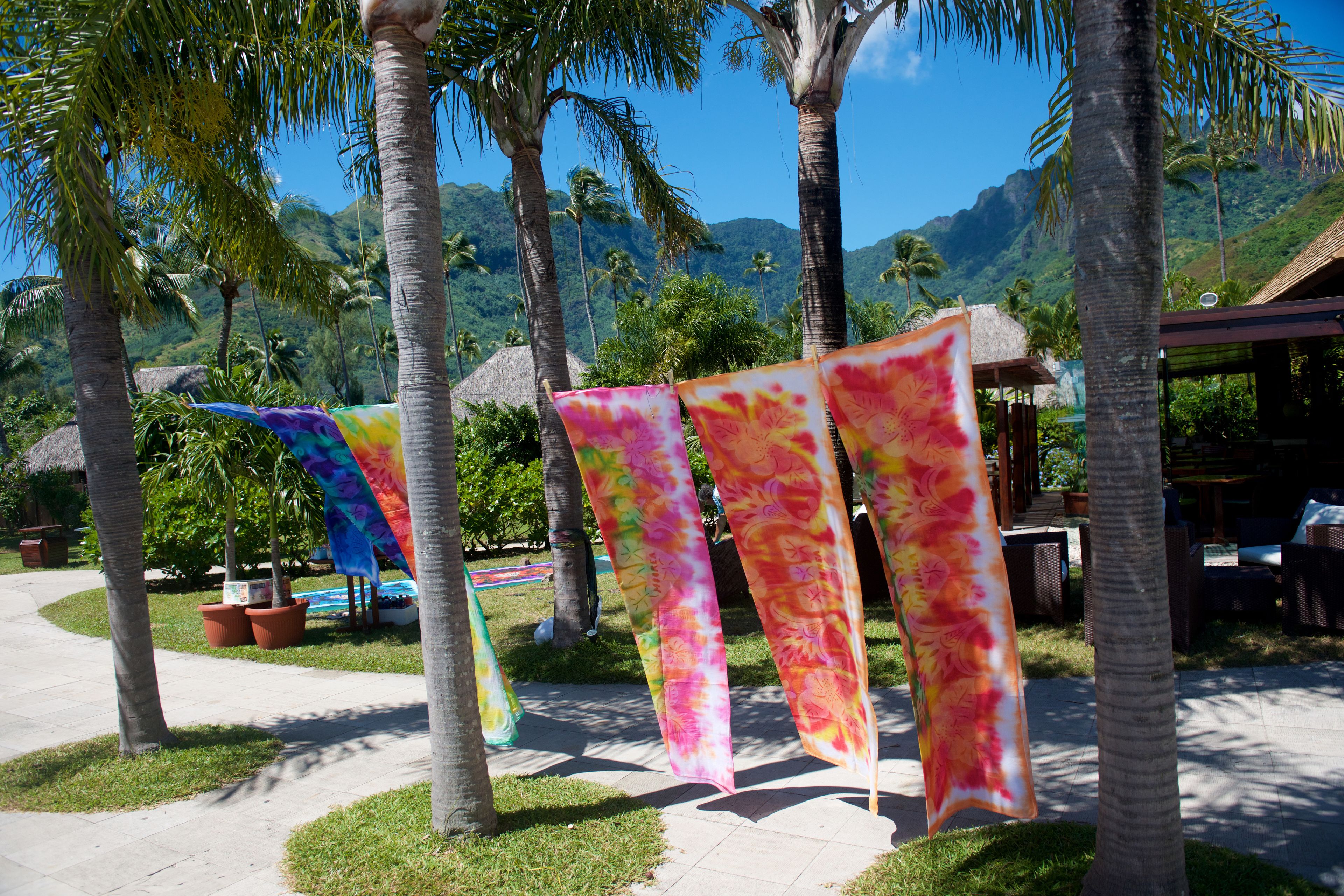 A tropical resort with palm trees, a thatched-roof structure, and colorful flags.