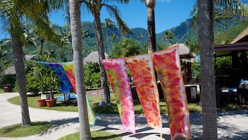 A tropical resort with palm trees, a thatched-roof structure, and colorful flags.