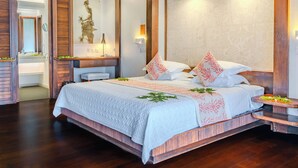 A spacious bedroom with a large bed, a wooden headboard, a nightstand, and a wall-mounted lamp. - Manava Beach Resort & Spa Moorea (Moorea-Maiao)