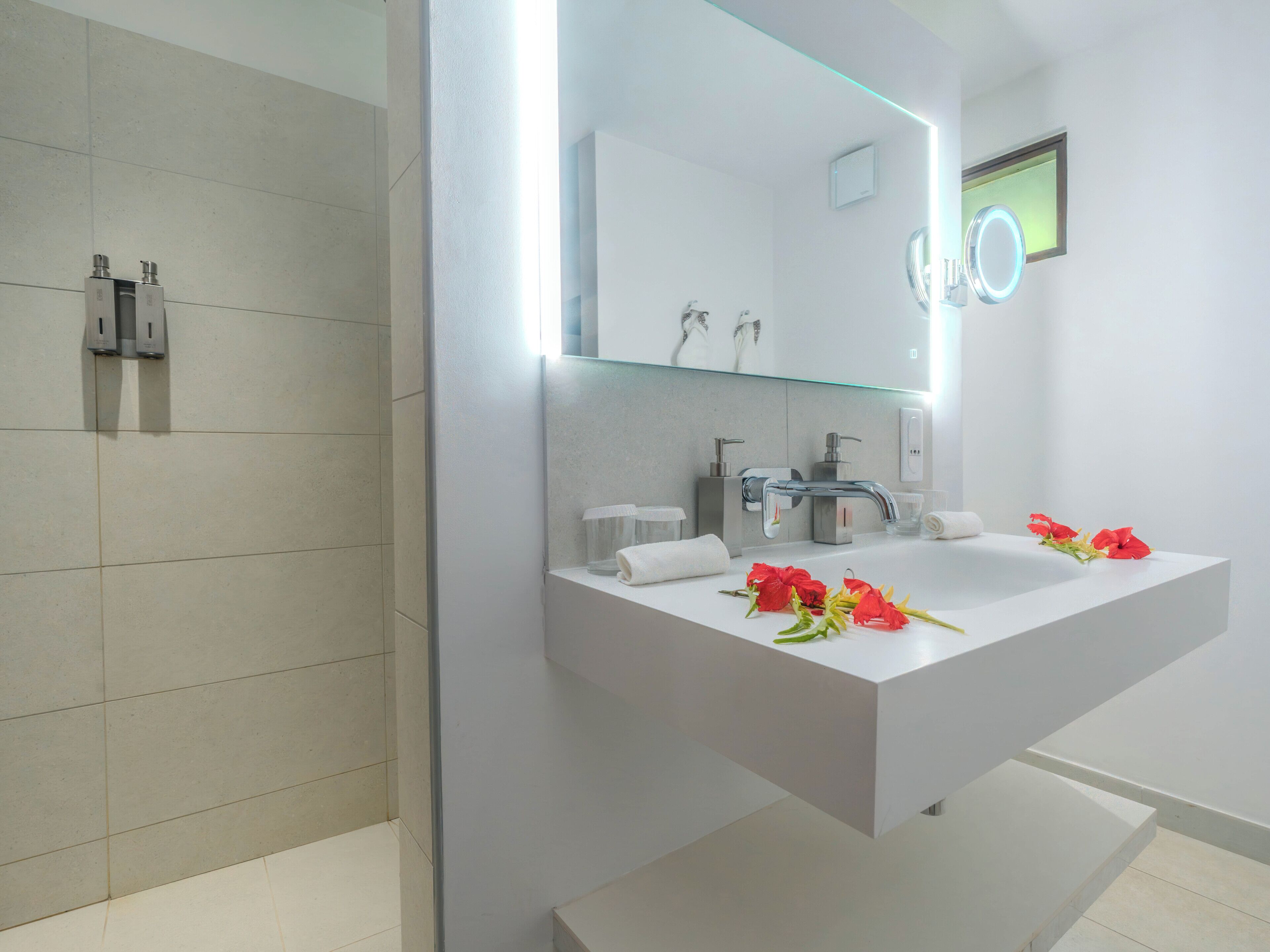 Un baño moderno con un espejo grande, zona de ducha y tocador con lavamanos.