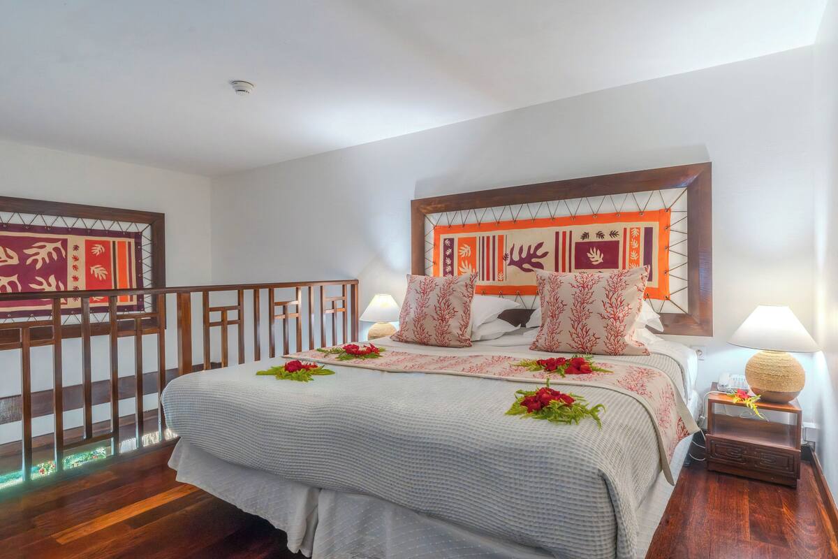 A neatly arranged hotel room with a bed, a nightstand, a lamp, and a decorative headboard.