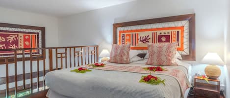 A neatly arranged hotel room with a bed, a nightstand, a lamp, and a decorative headboard.