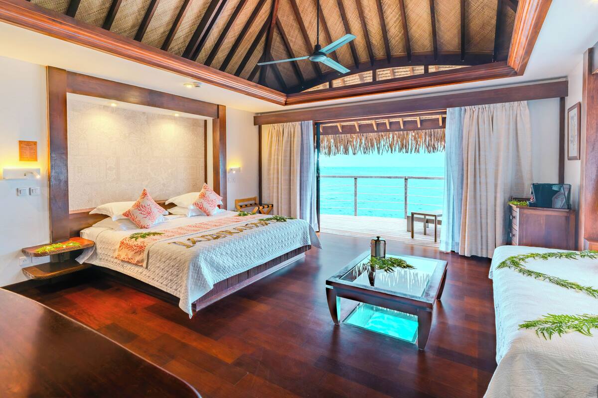 A spacious bedroom with a large bed, a glass coffee table, and a view of the ocean.