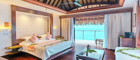 A spacious bedroom with a large bed, a glass coffee table, and a view of the ocean.