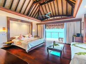 Un dormitorio amplio con una cama grande, una mesa de centro de vidrio y vistas al océano.