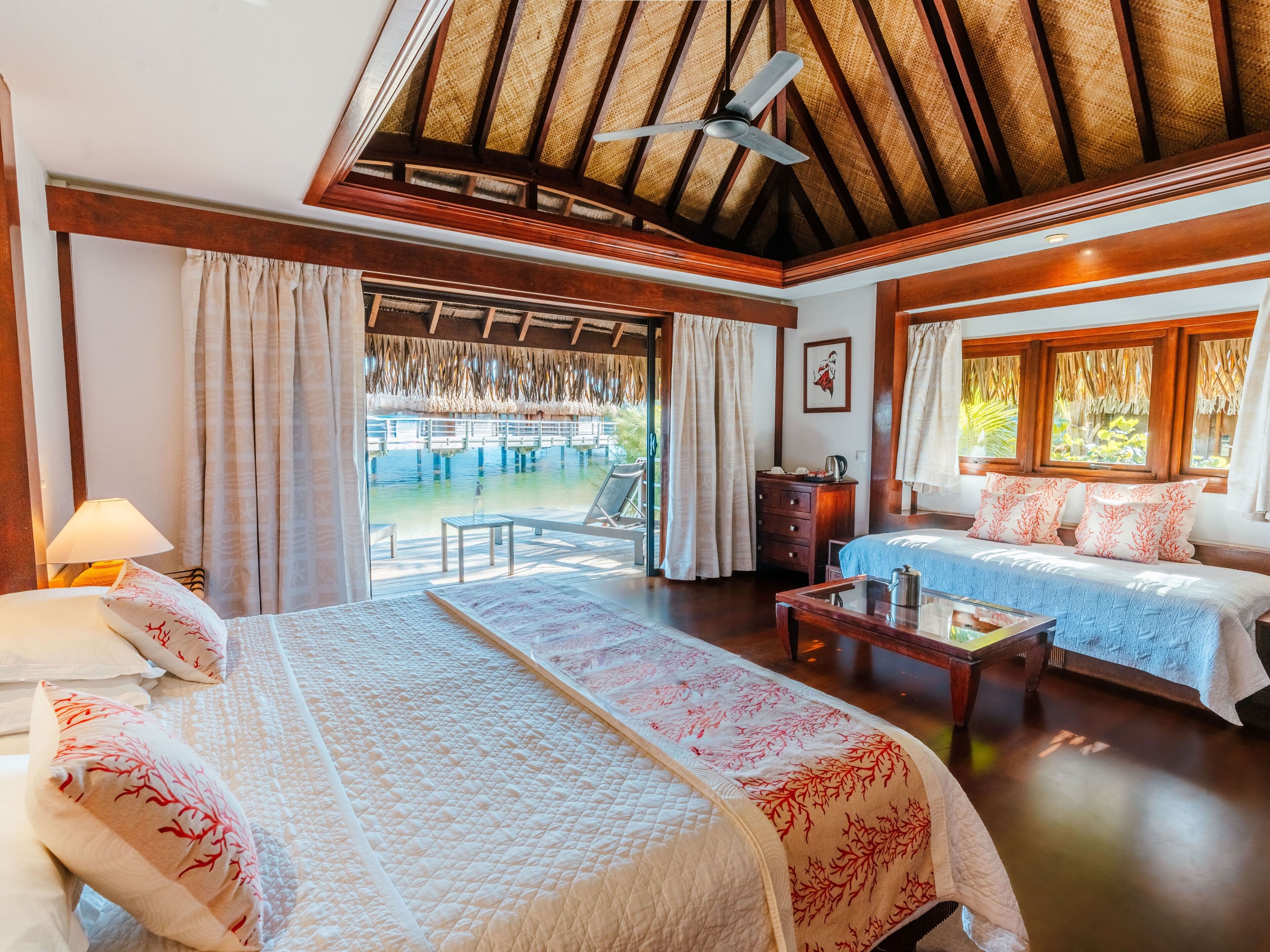 A hotel room with a bed, a sofa, a table, and a view of a pool and outdoor area.