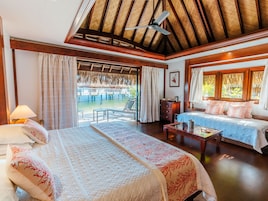 A hotel room with a bed, a sofa, a table, and a view of a pool and outdoor area.