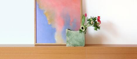 A bed with a white pillow and a green vase with flowers on a wooden headboard.