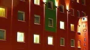 Un edificio de hotel de varios pisos con ventanas iluminadas y un letrero 'HOTEL' visible en el lado derecho.