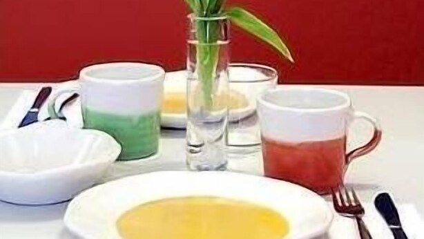 Una mesa con un jarrón de tulipanes, un plato con una sustancia amarilla y dos tazas de té.