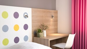 Un dormitorio moderno con cabecera de madera, una mesita de noche con una planta y una silla blanca.