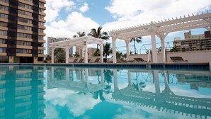 A swimming pool with a reflection of the surrounding buildings and palm trees. - Waikiki Monarch Hotel (Honolulu)