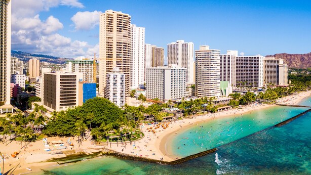 A coastal cityscape with high-rise buildings, a beach, and clear blue waters. - Waikiki Monarch Hotel (Honolulu)
