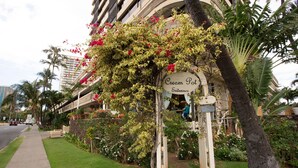 A hotel entrance with a sign reading "Cream Pot Entrance," surrounded by lush greenery and palm trees. - Waikiki Monarch Hotel (Honolulu)