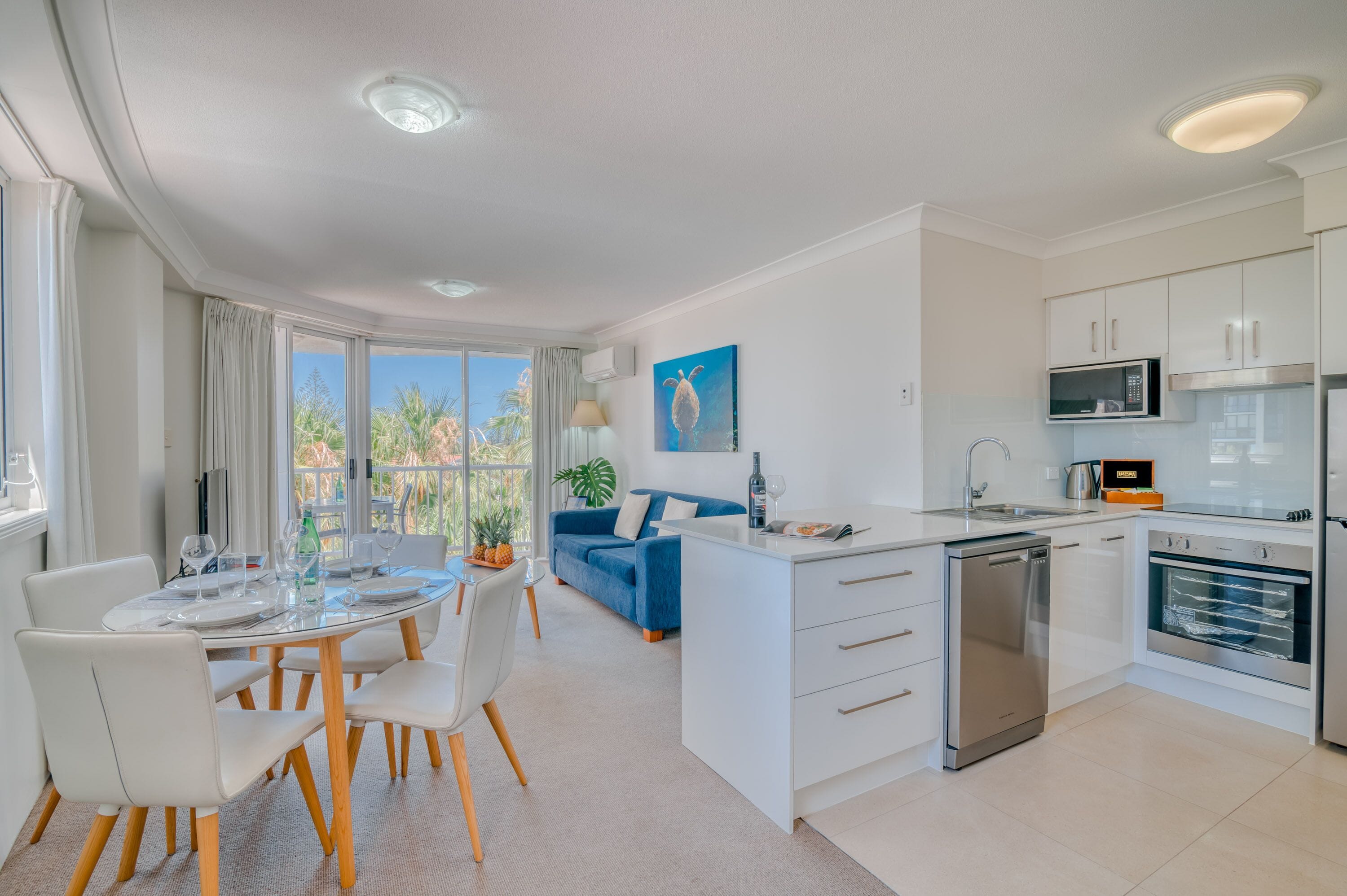 A modern kitchen with white cabinetry, a built-in microwave, and a stainless steel dishwasher.