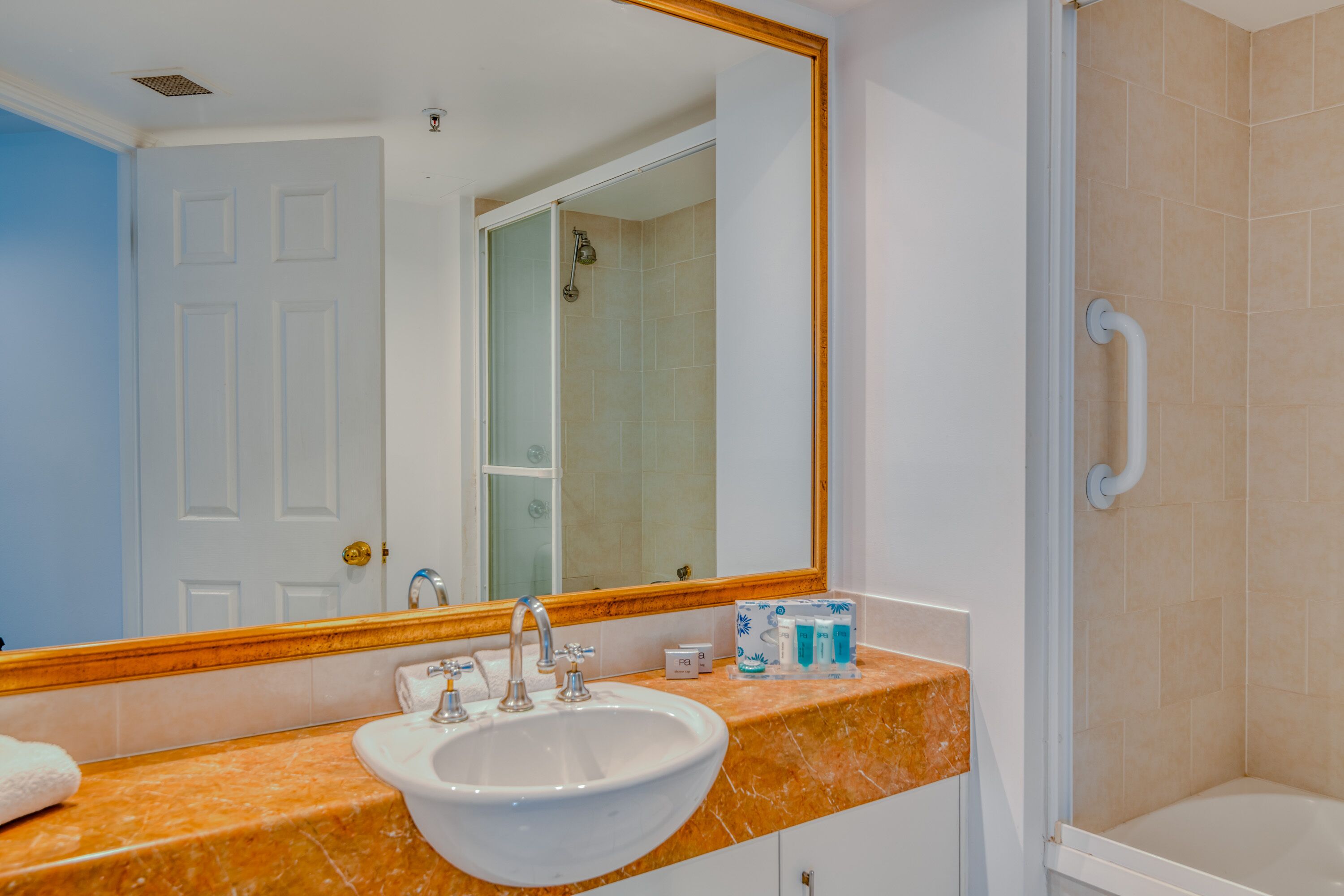 A bathroom with a white sink, a mirror, and a shower area.