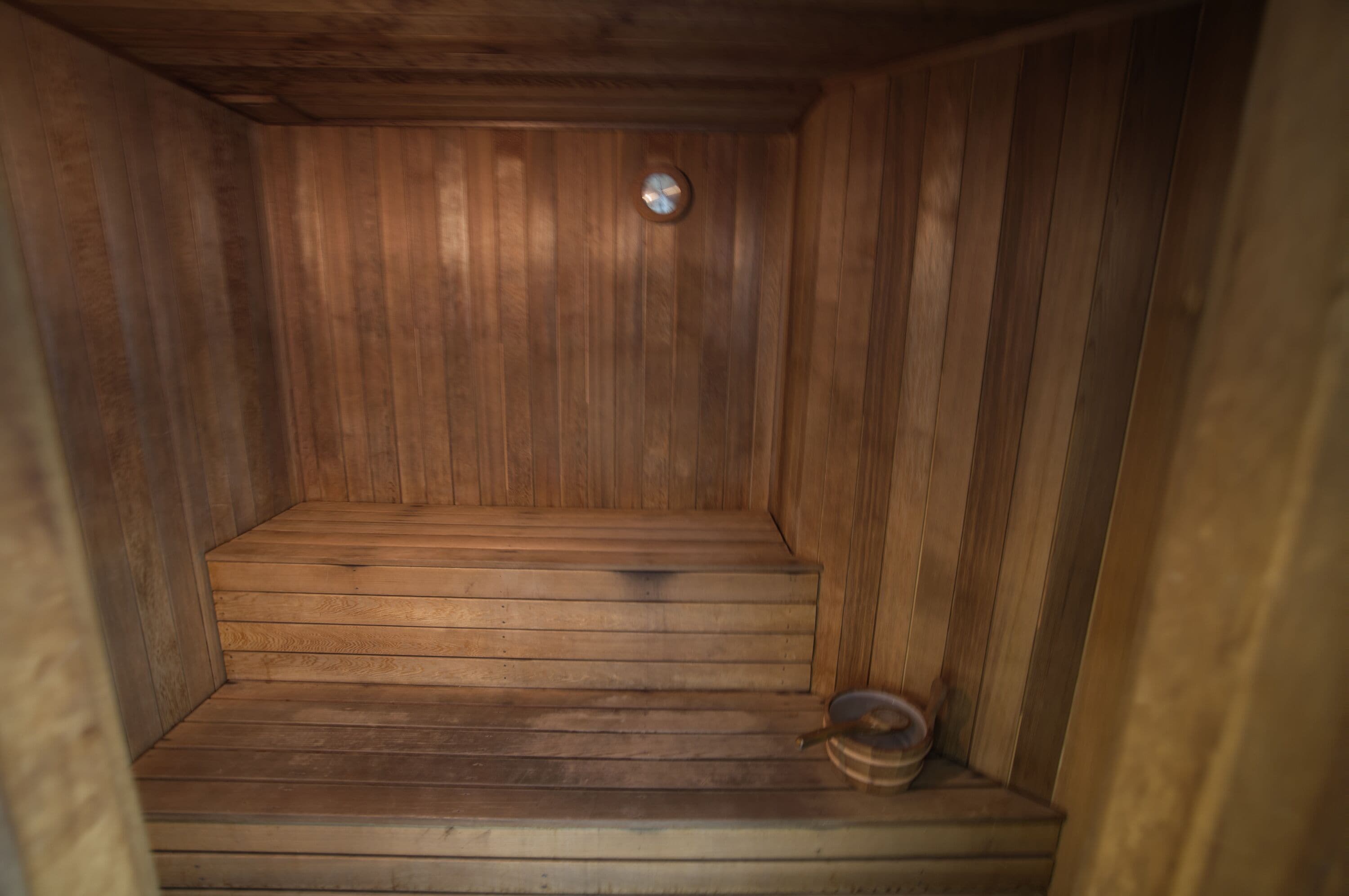 A wooden sauna with a bench and a small bowl.