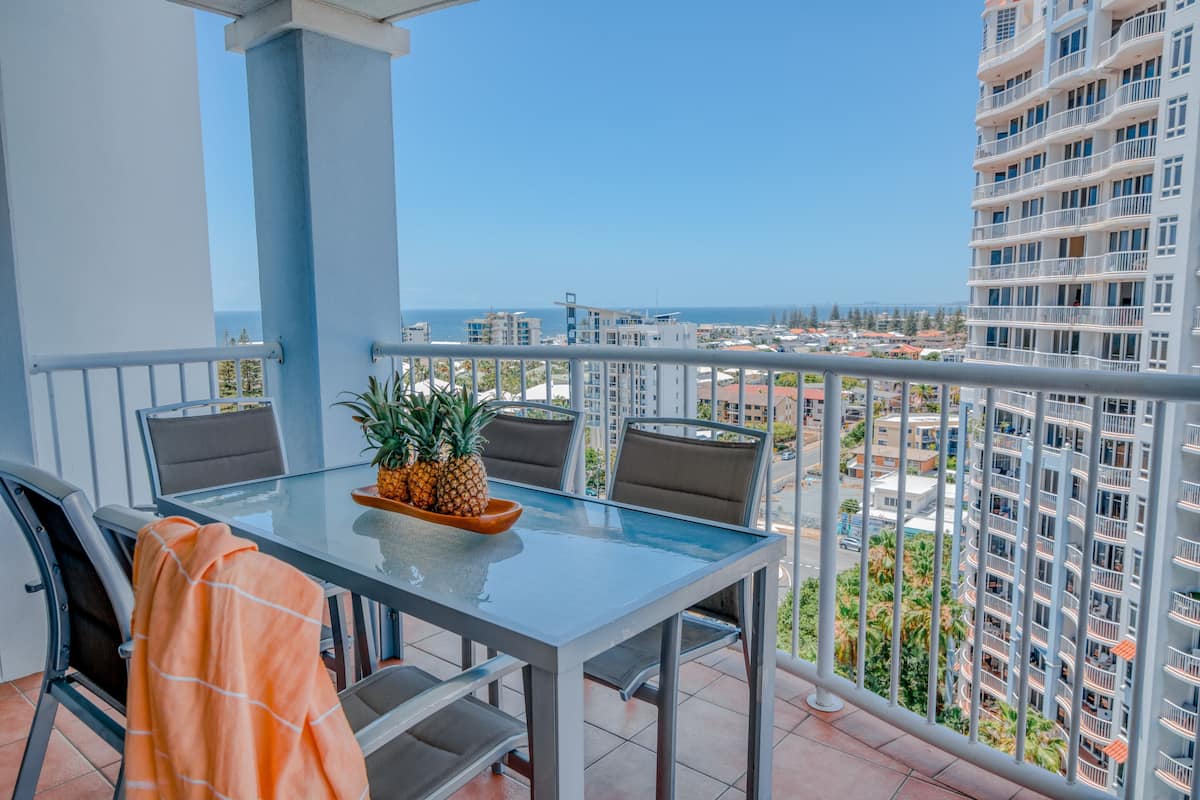 A balcony with a glass table, chairs, and a pineapple centerpiece.