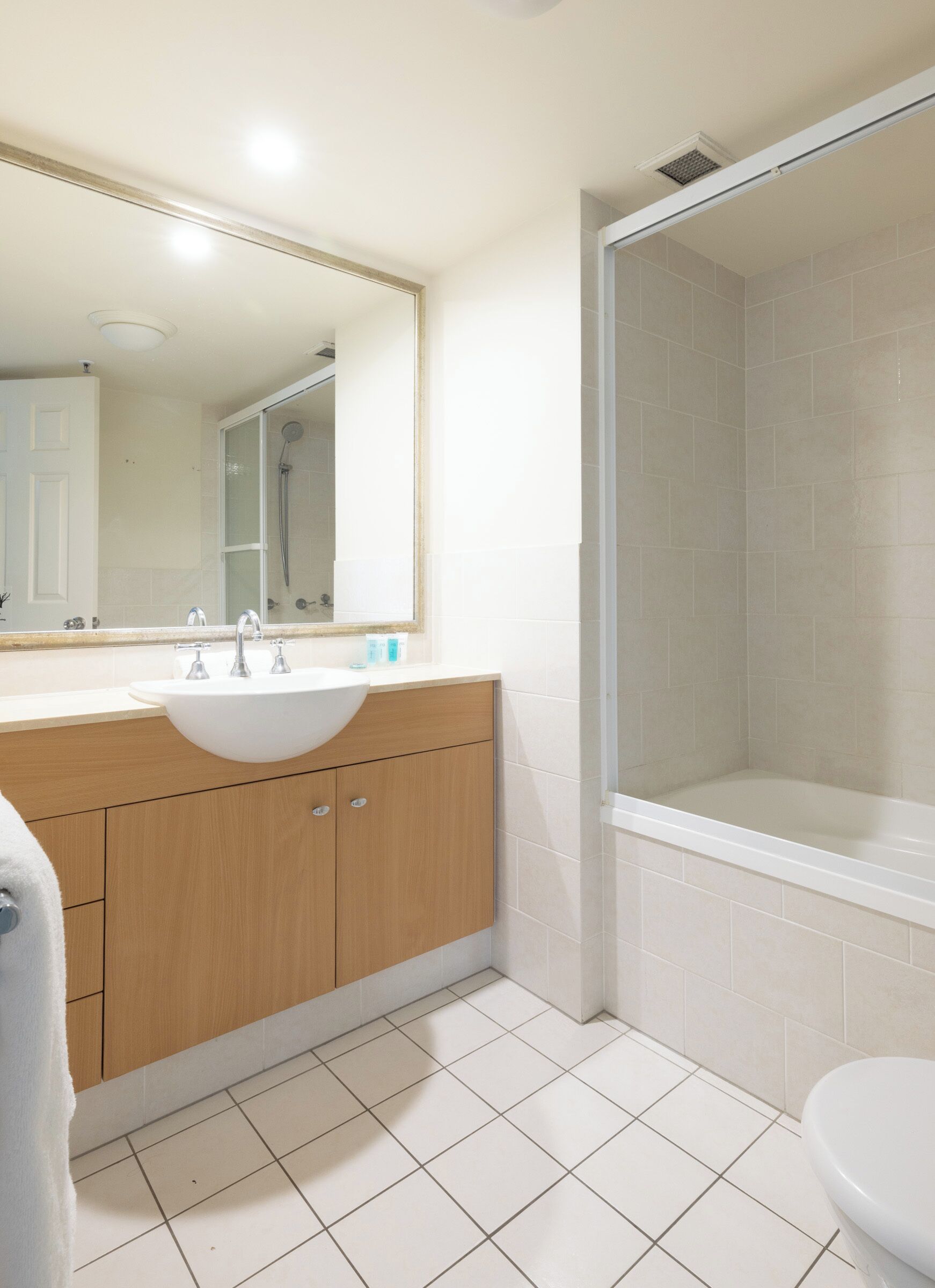 A bathroom with a sink, mirror, shower, and toilet.