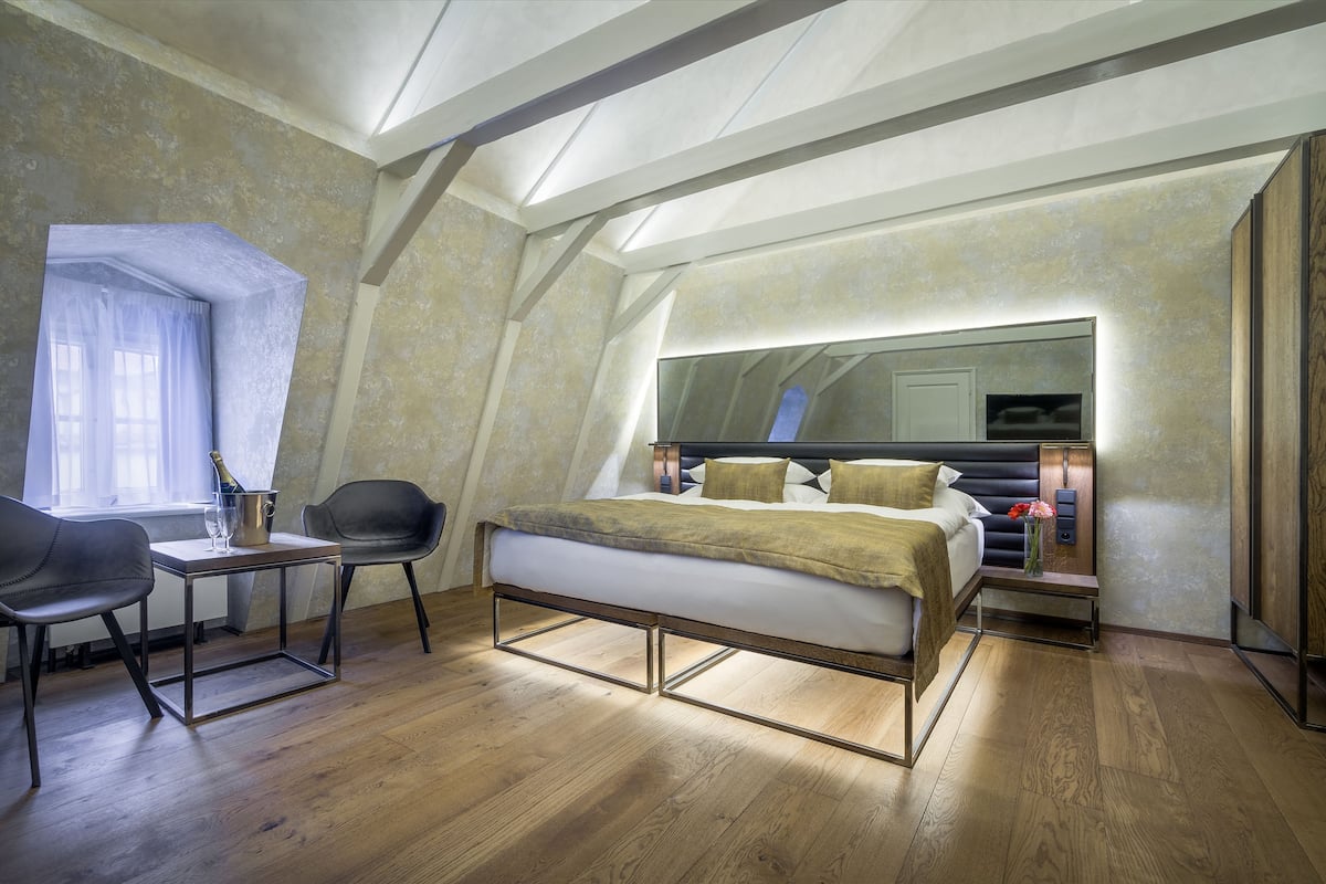 A bedroom with a bed, bedside tables, a desk with a chair, and a window with curtains.