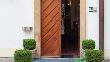 Entrada de hotel con puerta de madera, una placa con el nombre "WALSTEIN" y dos macetas a ambos lados.