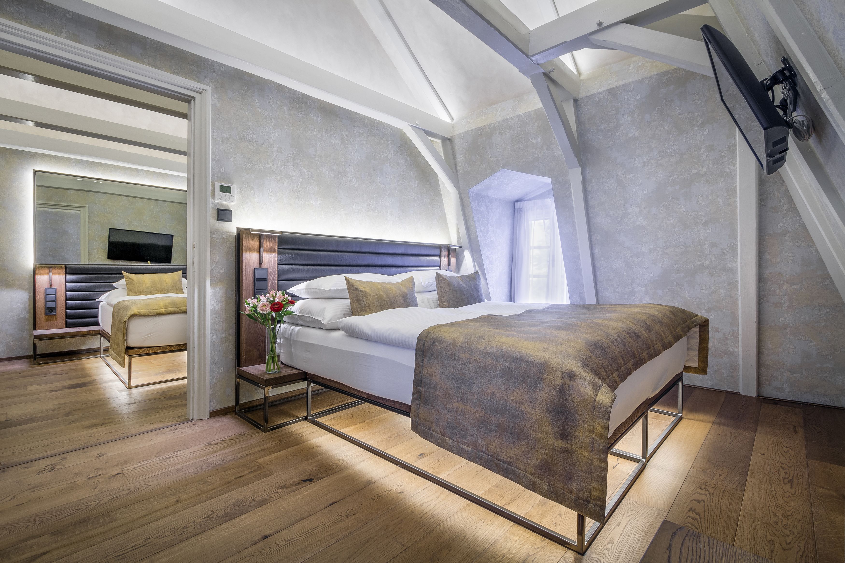 Une chambre moderne avec un grand lit, une table de chevet, un miroir et un téléviseur.