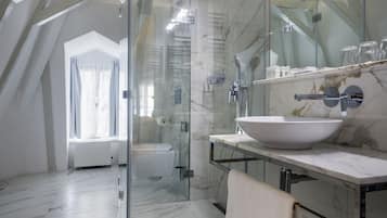 A modern bathroom with a glass-enclosed shower, a white sink, and a marble floor.