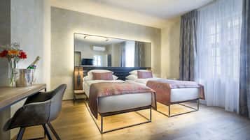 A modern hotel room with two beds, a desk, and a chair.