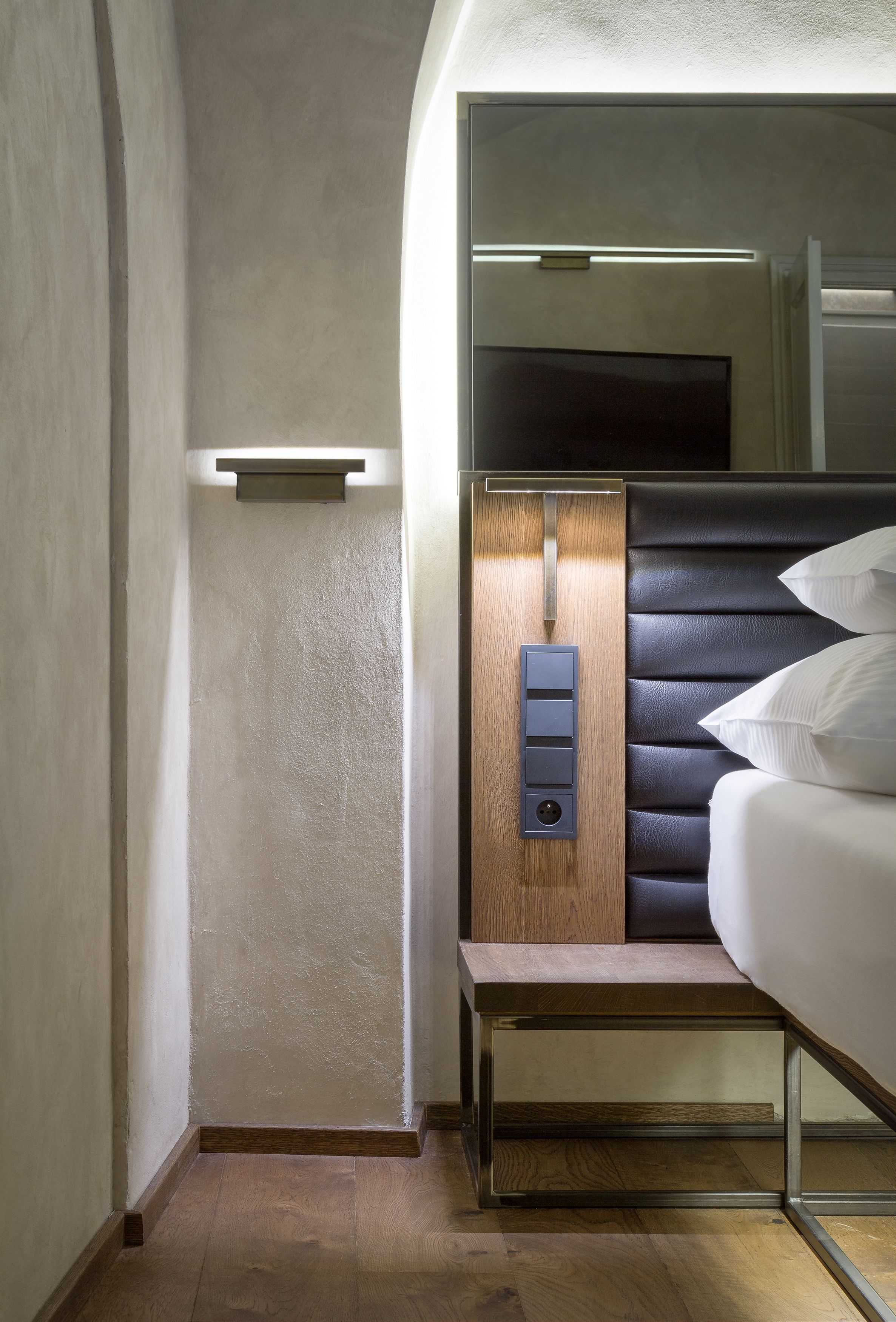 Une chambre d’hôtel moderne équipée d’un lit, d’un panneau de commande et d’une petite étagère.