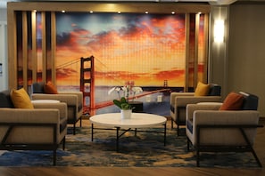 Ein Zimmer mit vier Sesseln, einem runden Couchtisch und einem großflächigen Wandbild der Golden Gate Bridge.