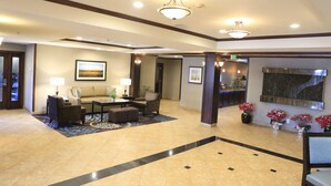 A hotel lobby with a reception desk, seating area, and decorative plants. - Staybridge Suites Silicon Valley by IHG (Milpitas)