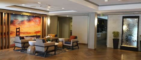 A lobby with a herringbone floor, a large wall mural, and a seating area with sofas and a coffee table.