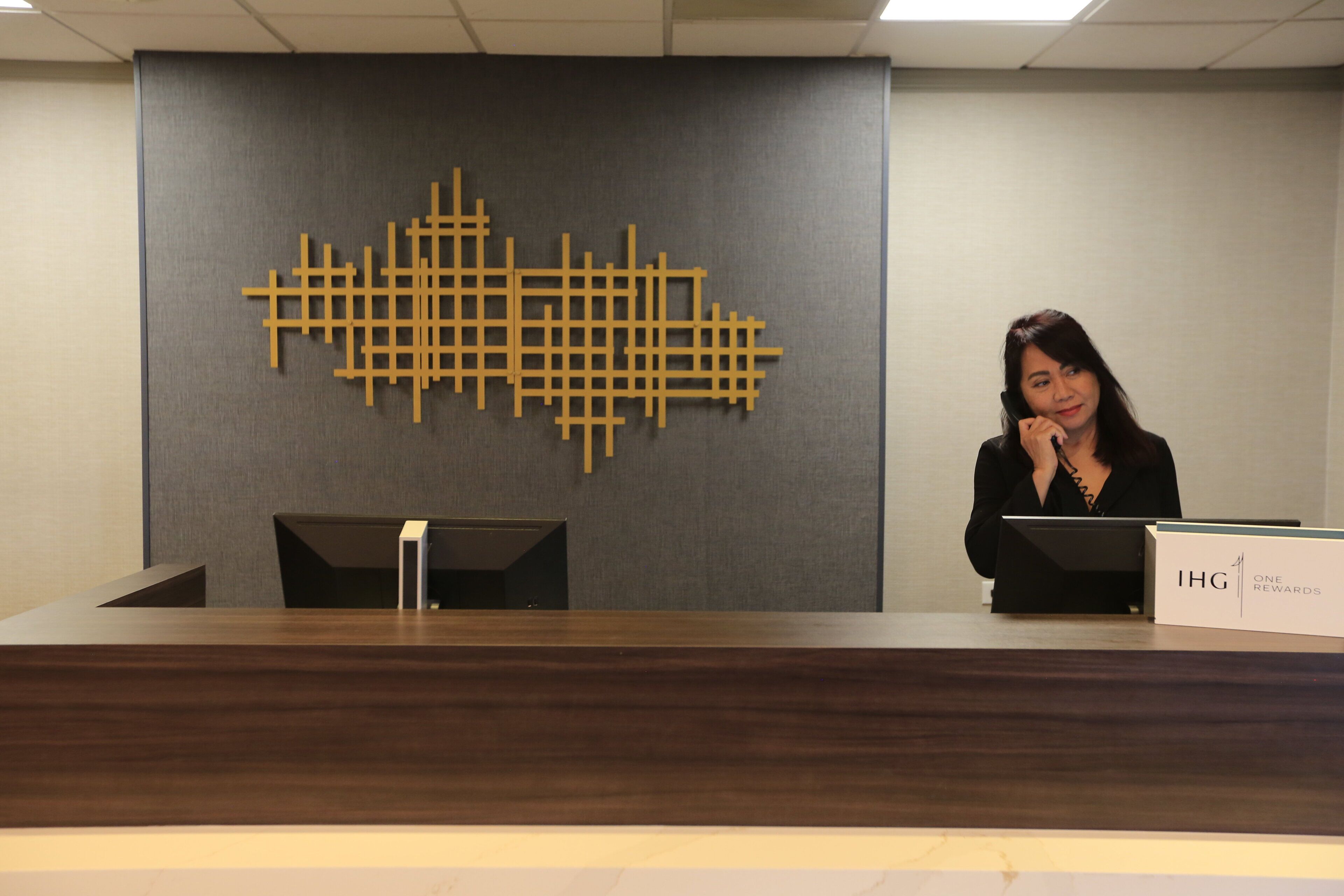 A reception desk with a modern design, a nameplate, and a decorative wall piece.