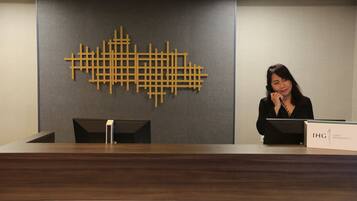 A reception desk with a modern design, a nameplate, and a decorative wall piece.
