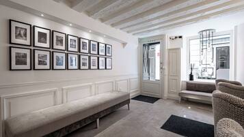 Un interior moderno con un largo banco, un sofá y una pared decorada con fotografías enmarcadas.